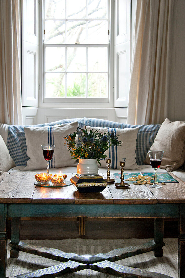 Rotwein und Kerzen mit Schnittblumen auf Couchtisch am Fenster des Hauses in Crantock Cornwall England UK