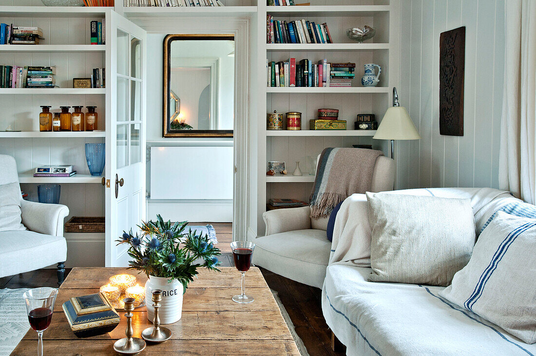 Lit candles and cut thistles on wooden coffee table in living room of Crantock home Cornwall England UK