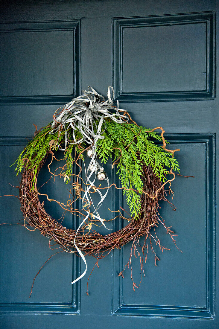 Weihnachtskranz mit silbernen Kugeln an türkisfarbener Eingangstür eines Hauses in Crantock, Cornwall, England UK