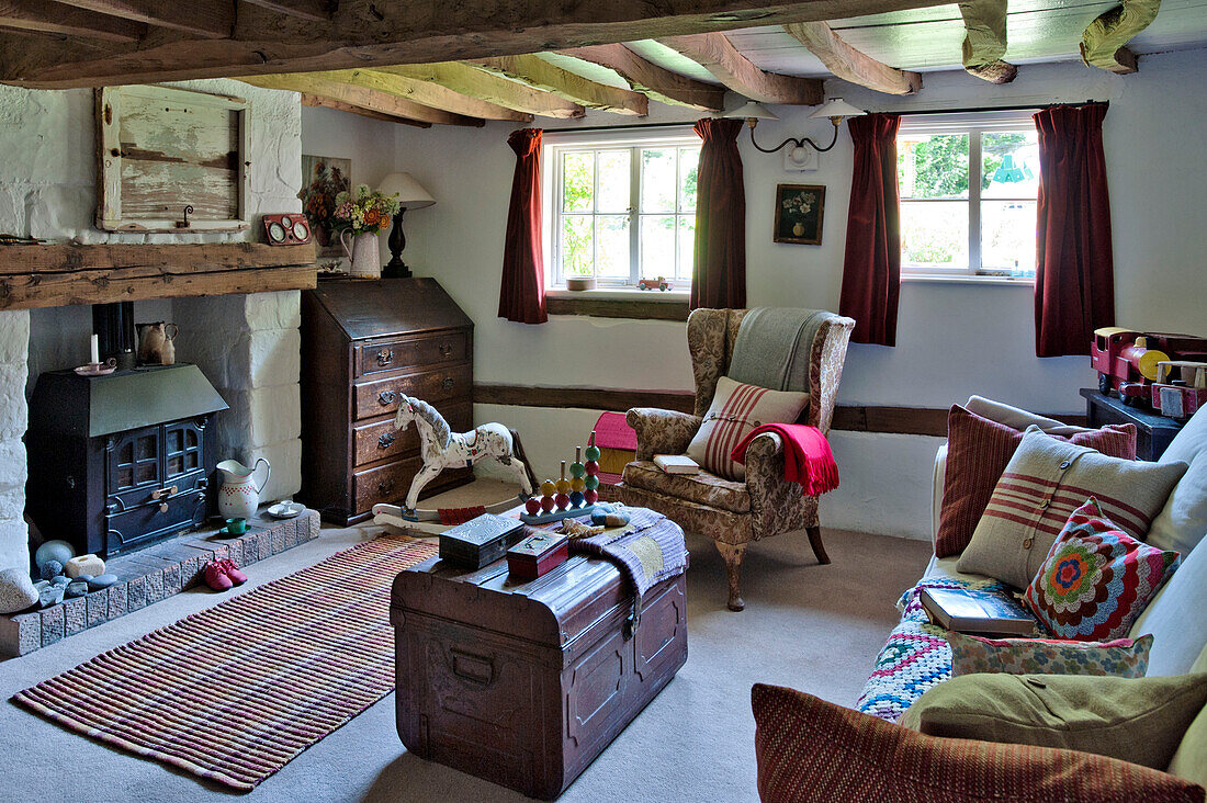 Ohrensessel und alte Truhe mit Schaukelpferd im Wohnzimmer eines Cottage in Cambridge England UK
