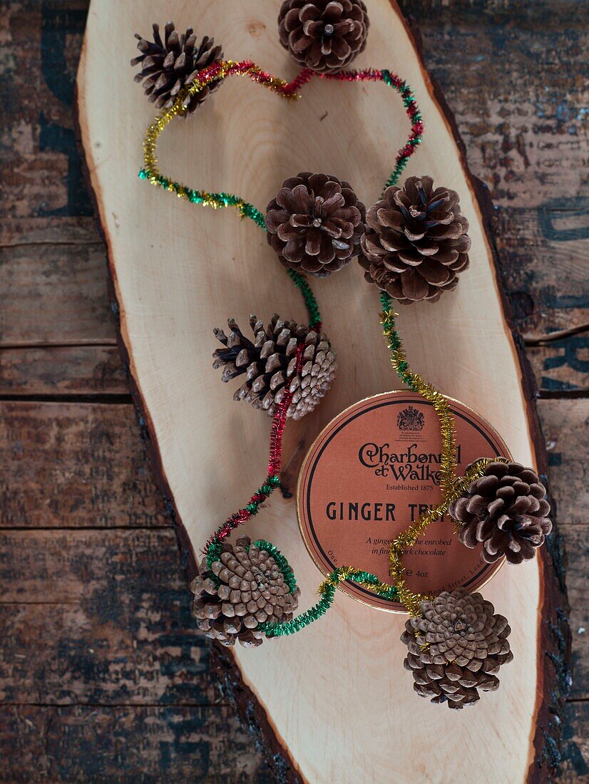 Pinecones and tinsel with ginger on wooden chopping board in London home England UK