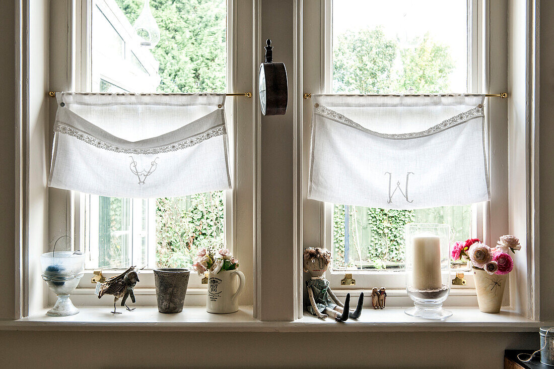 Embroidered window pockets above windowsill with vintage ornaments in Stamford home Lincolnshire England UK