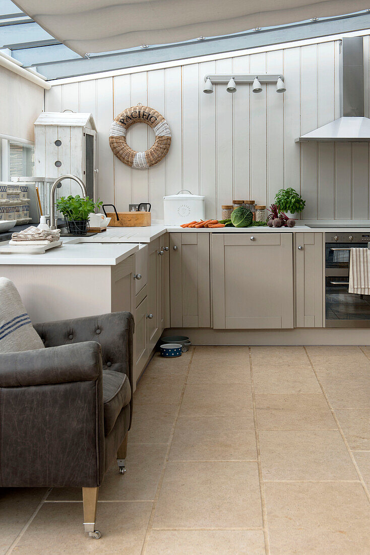 Brown leather armchair in panelled kitchen extension of Penzance farmhouse Cornwall England UK