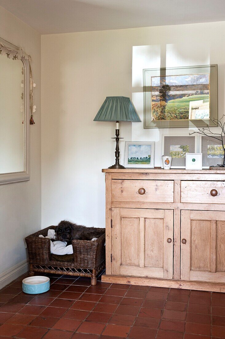 Grüne Lampe auf hölzernem Sideboard mit Hundekorb im Flur von Edworth cottage Bedfordshire England UK