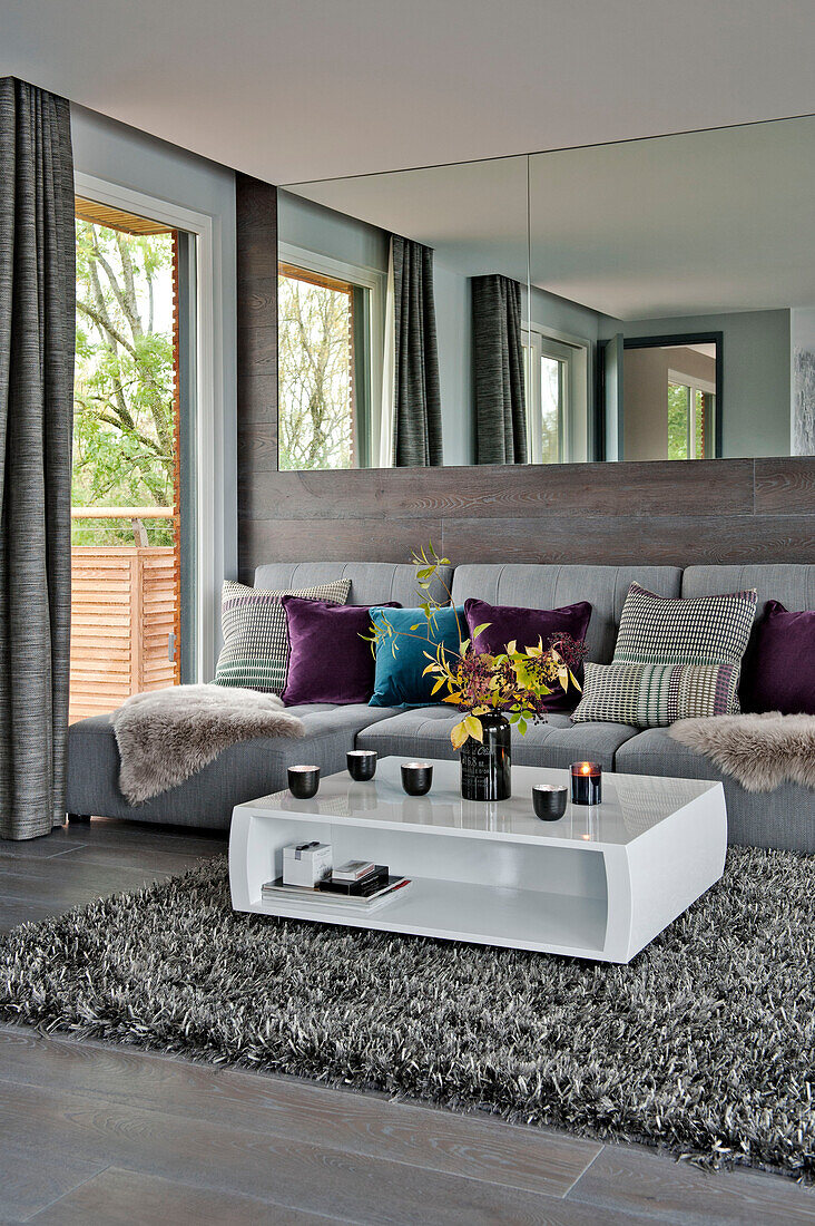 Tealights on low coffee table with sofa below large mirror in Lechlade living room Gloucestershire England UK