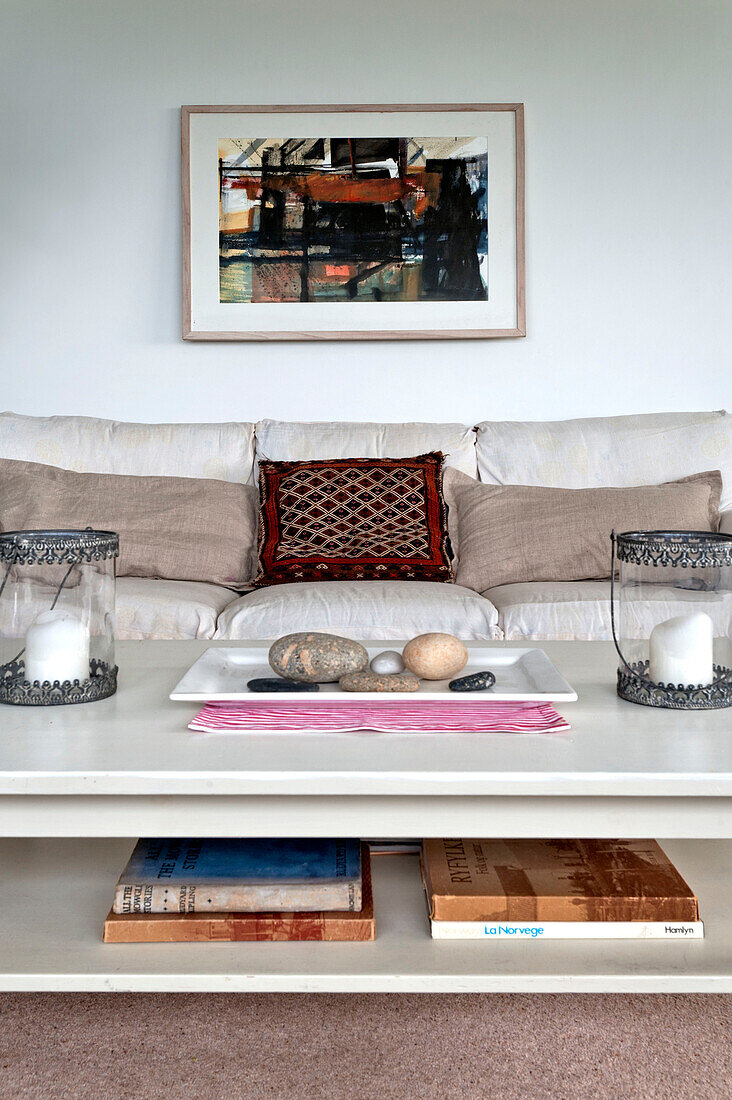 Framed artwork above sofa with pebbles and candles in beach house Cornwall England UK