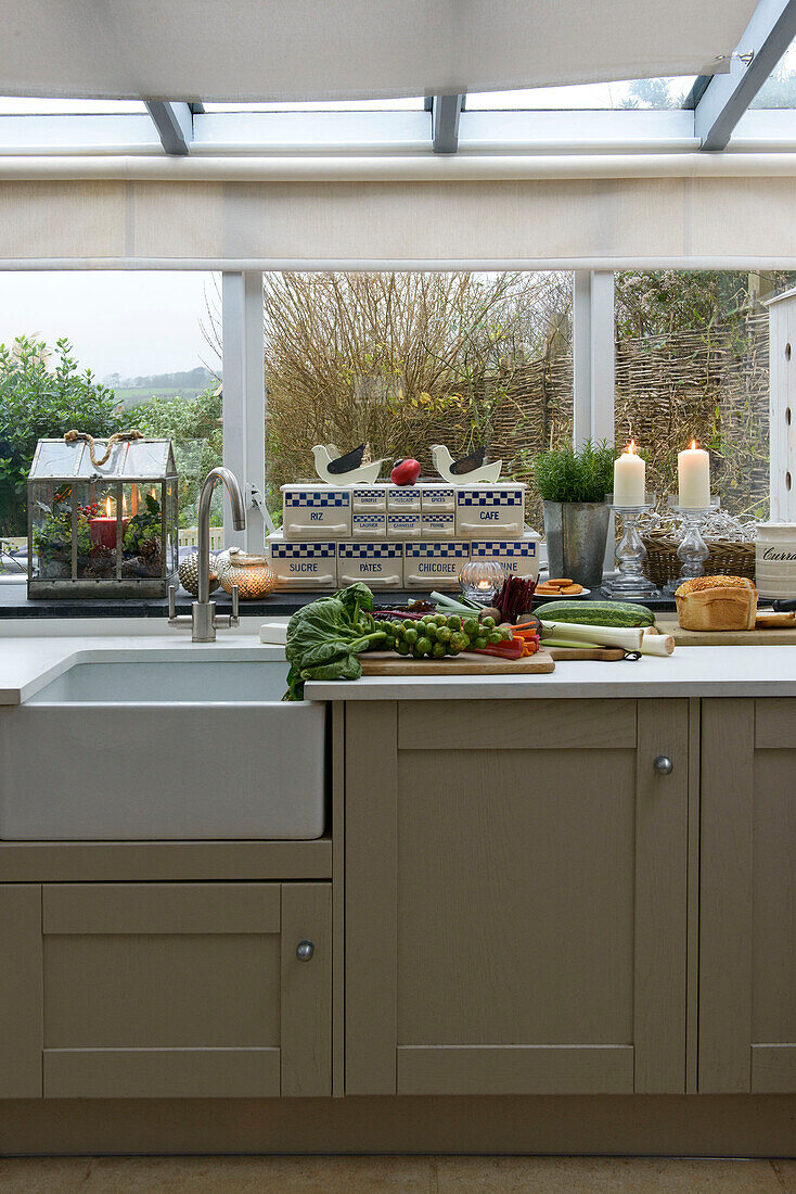 Fresh vegetables on kitchen worktop below window in Penzance home Cornwall UK