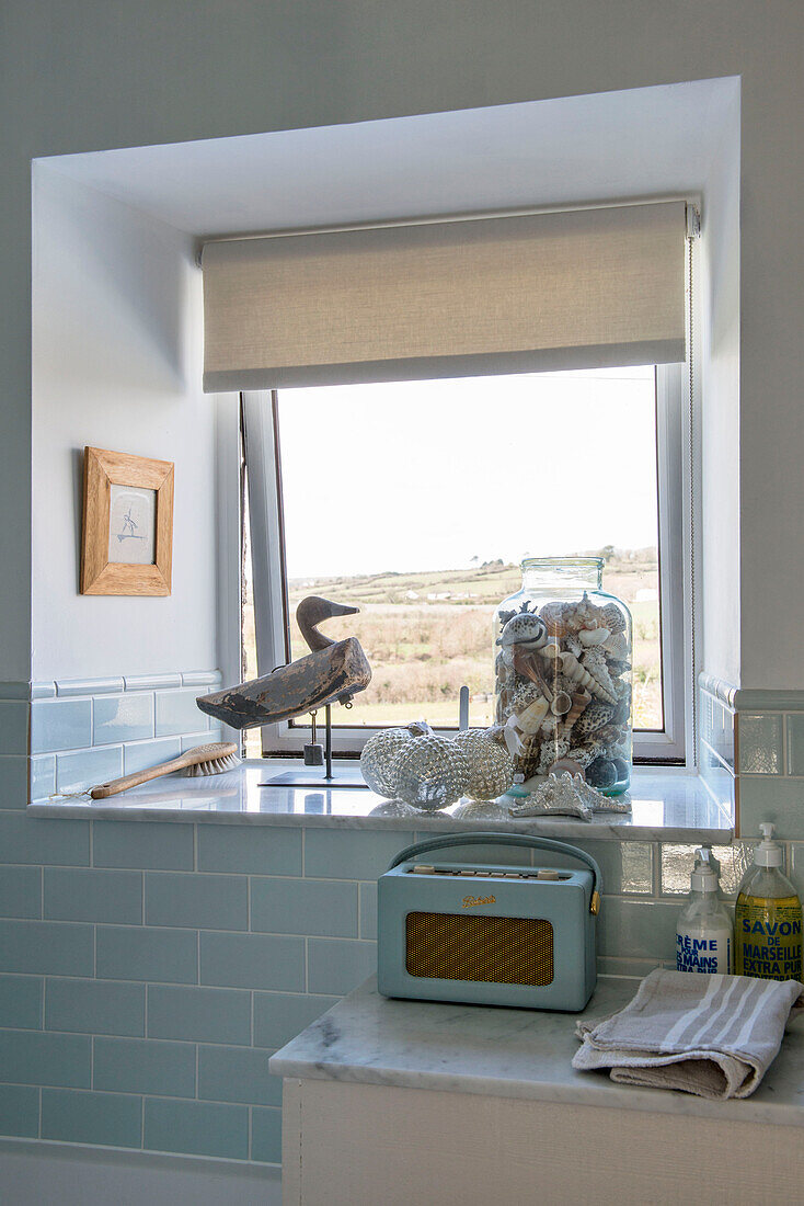 Muscheln und Kugeln auf der Fensterbank mit altem Radio im Badezimmer in Penzance Cornwall UK