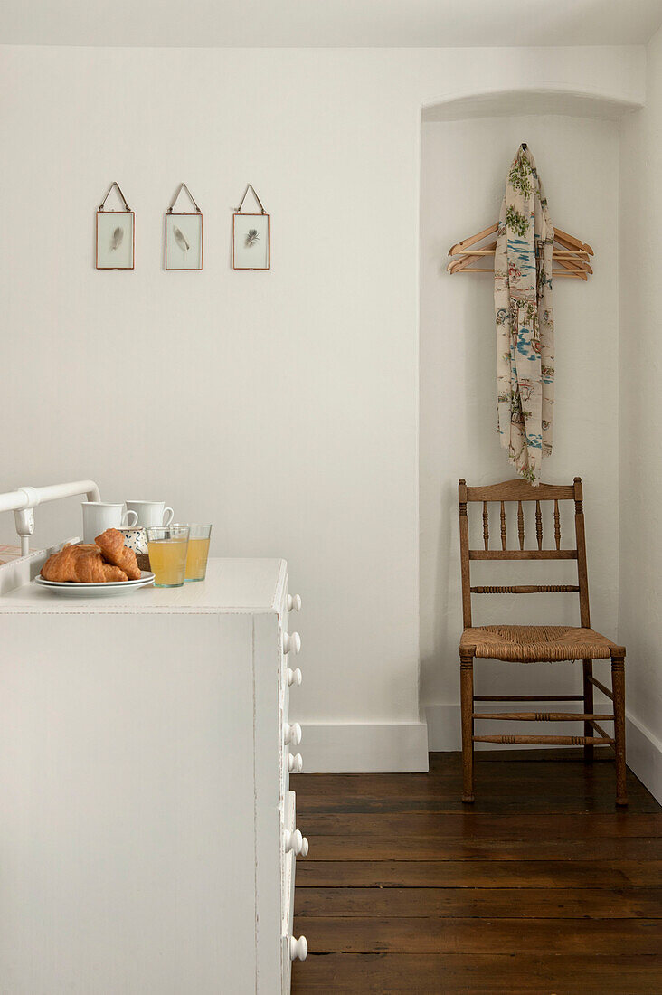 Wooden clothes hangers above wicker chair in alcove of Cornwall bedroom UK