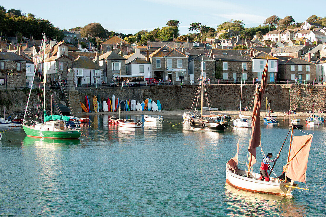 Mann hisst Segel im Hafen von Mousehole, Cornwall, UK