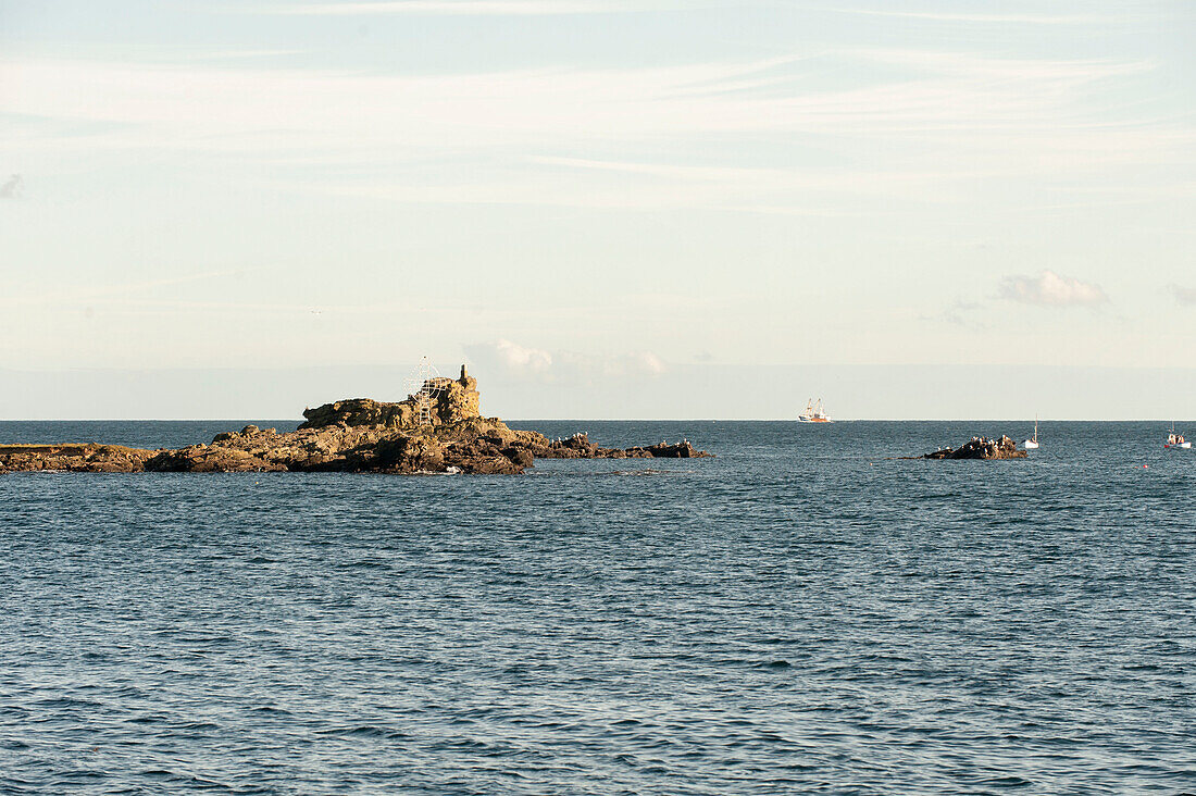 Rocky peninsula with boat on distant horizon Cornwall UK