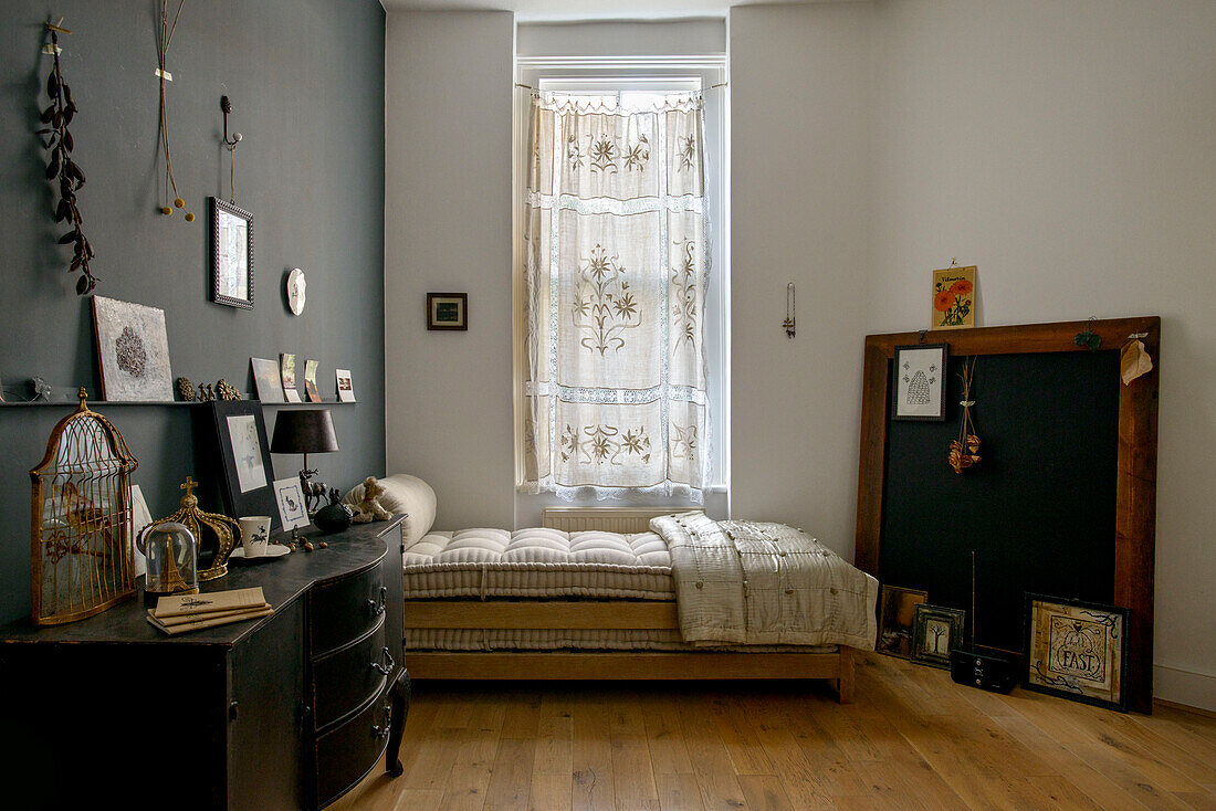 Black sideboard and single bed with embroidered net curtains in London home UK