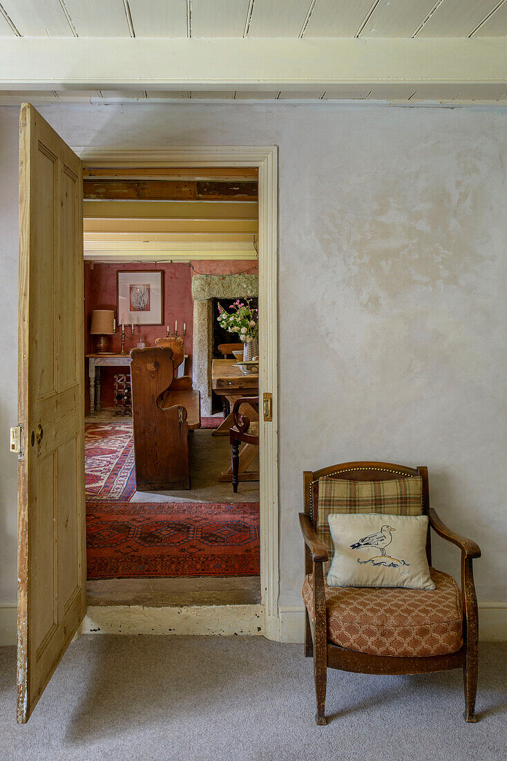 Small armchair with view through doorway in Helston farmhouse Cornwall UK