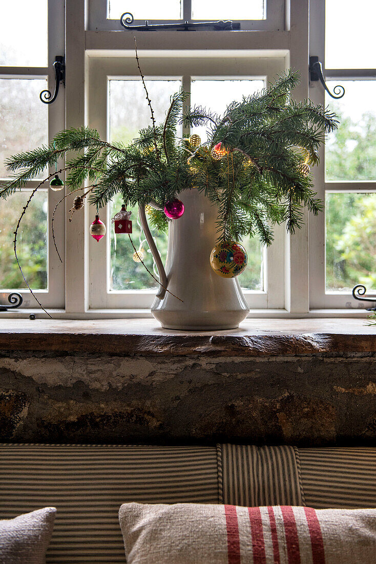 Evergreen foliage and Christmas baubles on windowsill in cottage St Erth UK