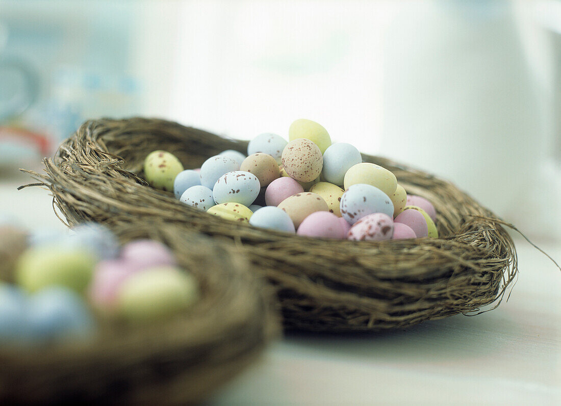 Bunte Schokoladen-Ostereier mit Zuckerüberzug in einem Korb in Form eines Vogelnestes