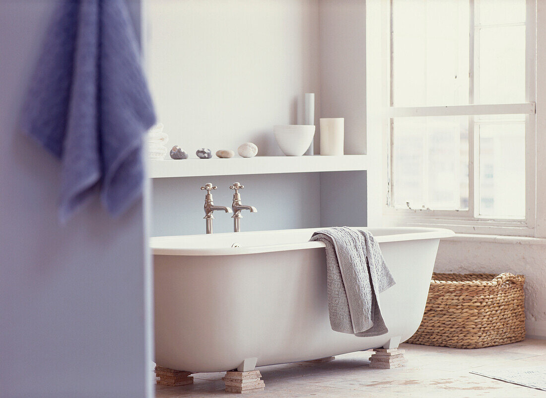 In Weiß und Hellblau dekoriertes Badezimmer mit Rolltop-Badewanne und Wäschekorb