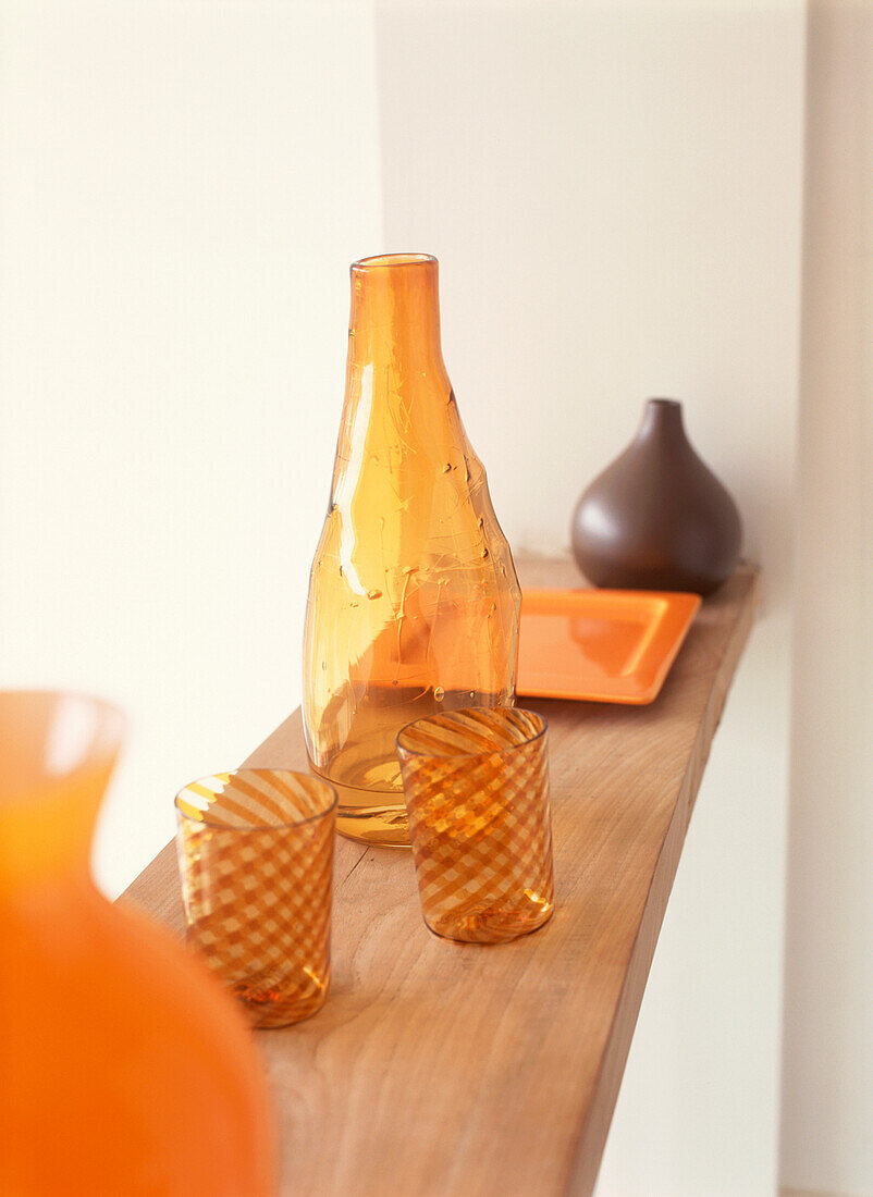 Display of contemporary orange and brown glassware & ceramics on shelf