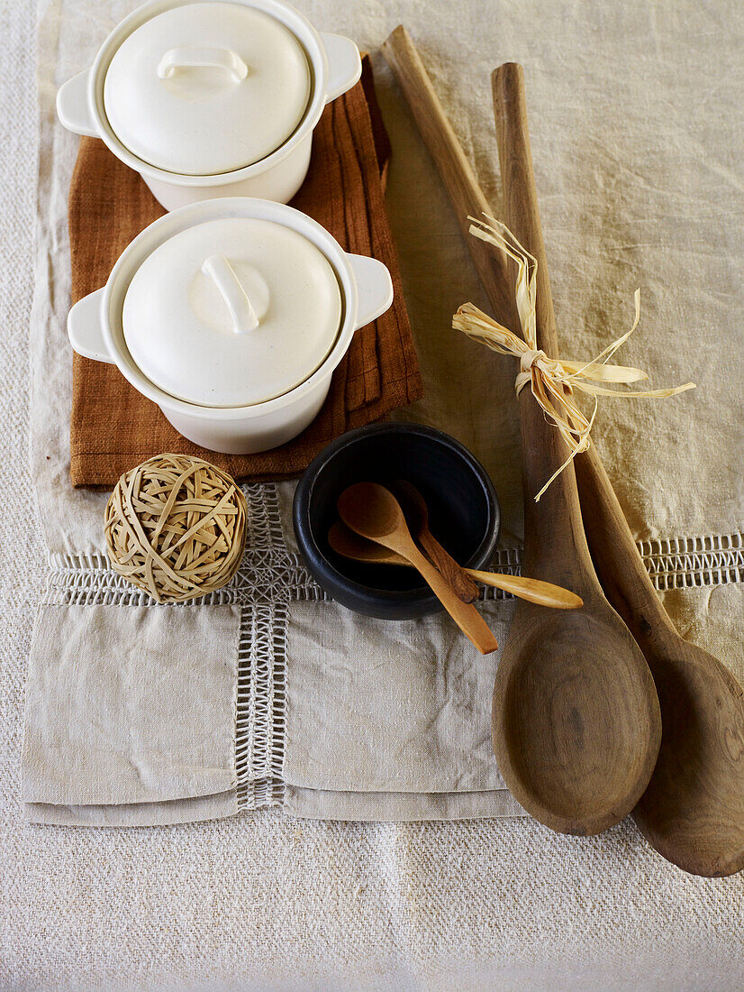 Wooden spoons and ceramic pots with elastic ball band on linen placemats