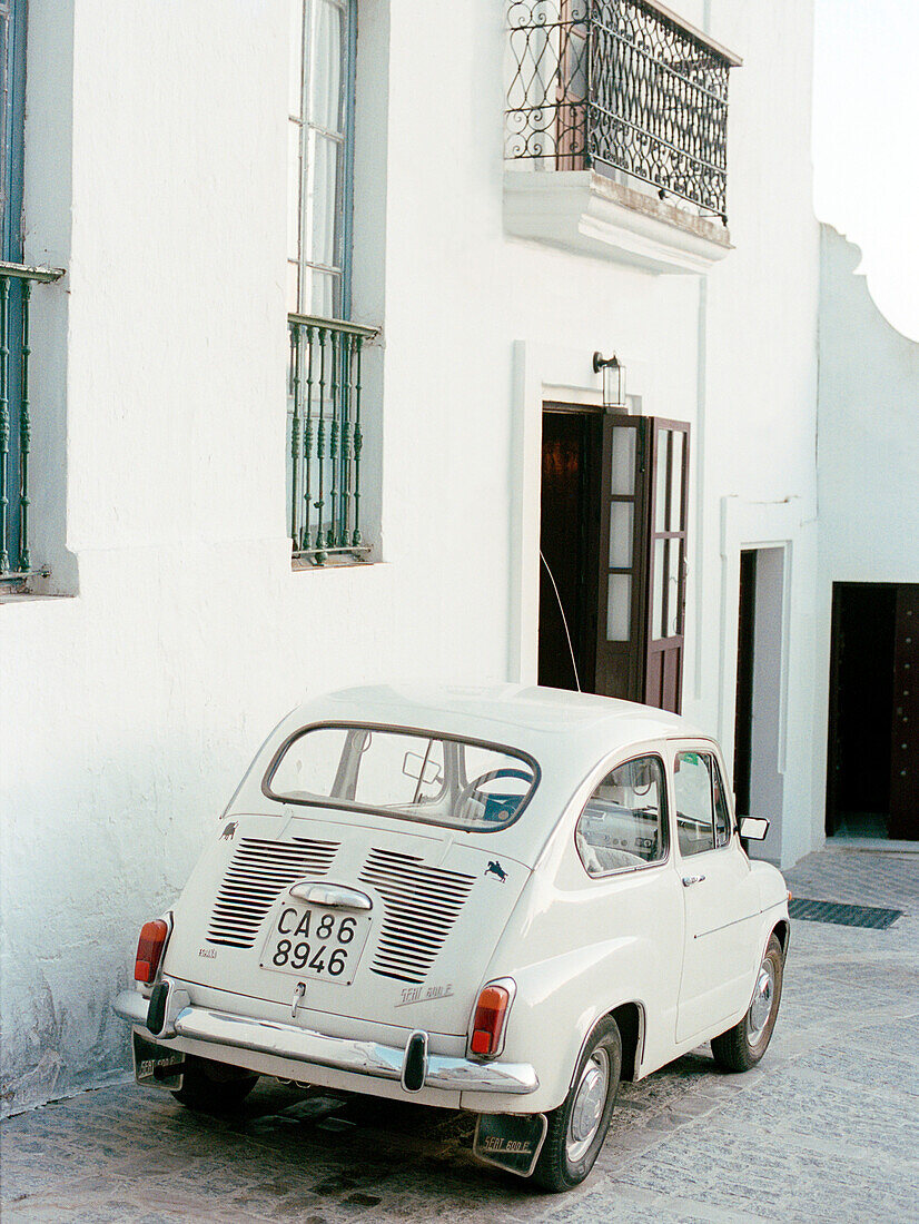 Weißer Oldtimer vor spanischem Stadthaus geparkt