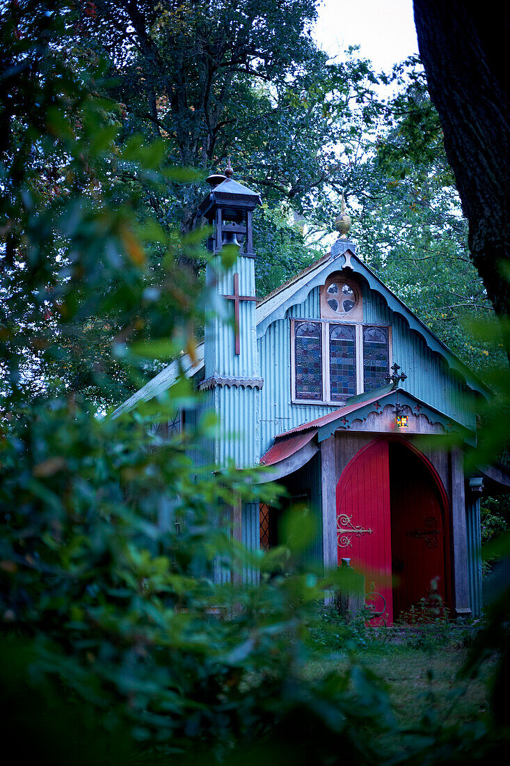 Woodland church viewed through leaves