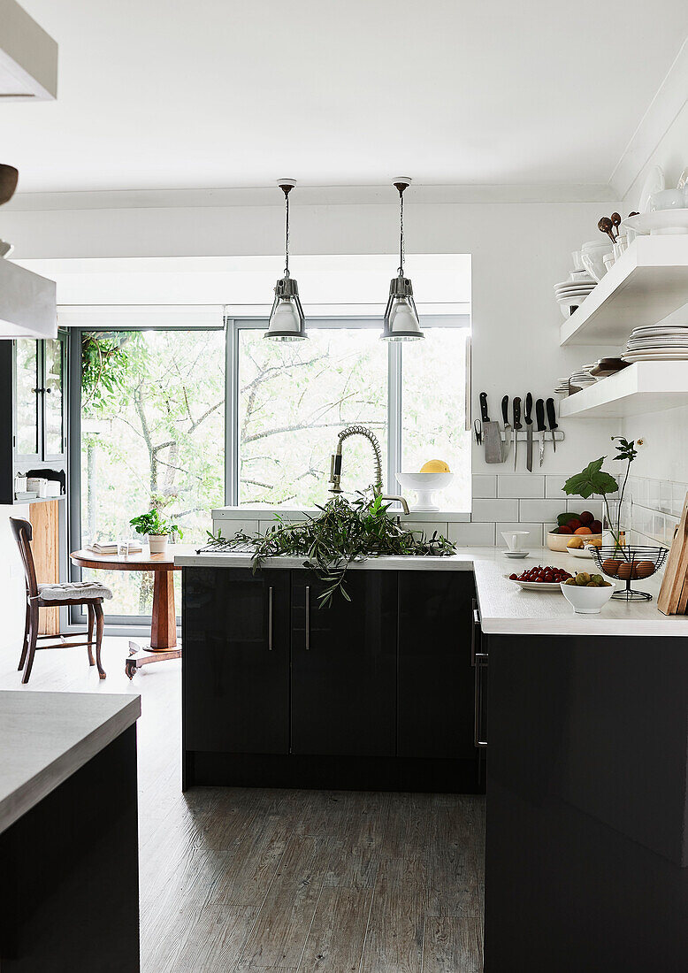 Cut leaves in sink of monochrome kitchen with table and chair at open patio door in Lyme Regis home Dorset UK