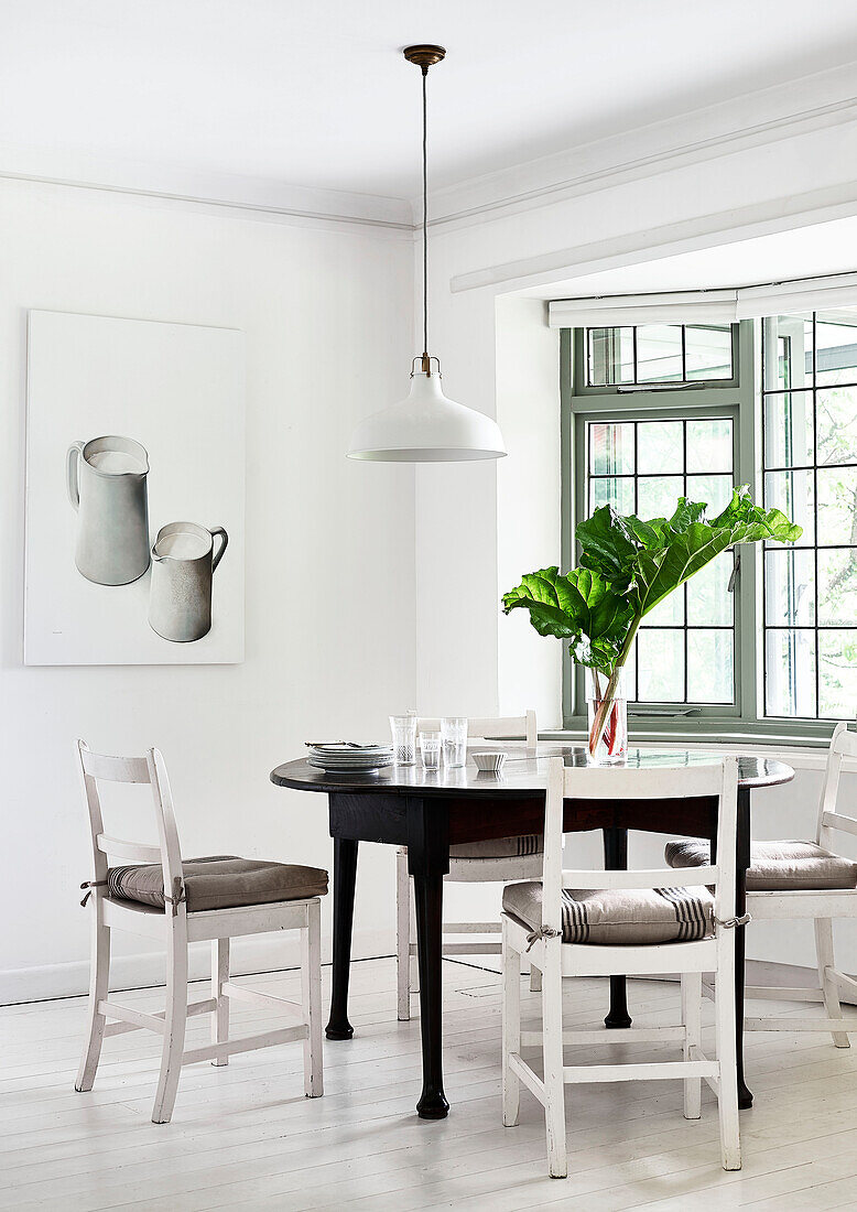 Cut leaves on dining table with chairs at window in Lyme Regis home Dorset UK