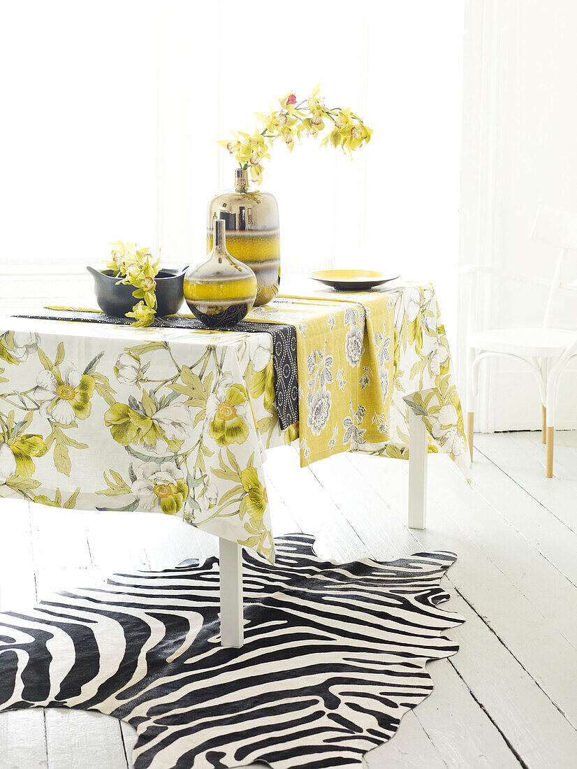 Frühlingsblumen auf Tisch mit Narzissentuch und Zebramuster-Teppich