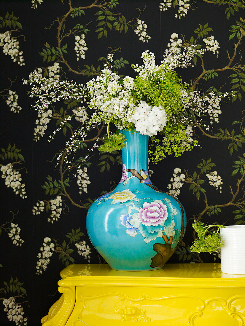 Cut flowers in oriental vase with black floral wallpaper