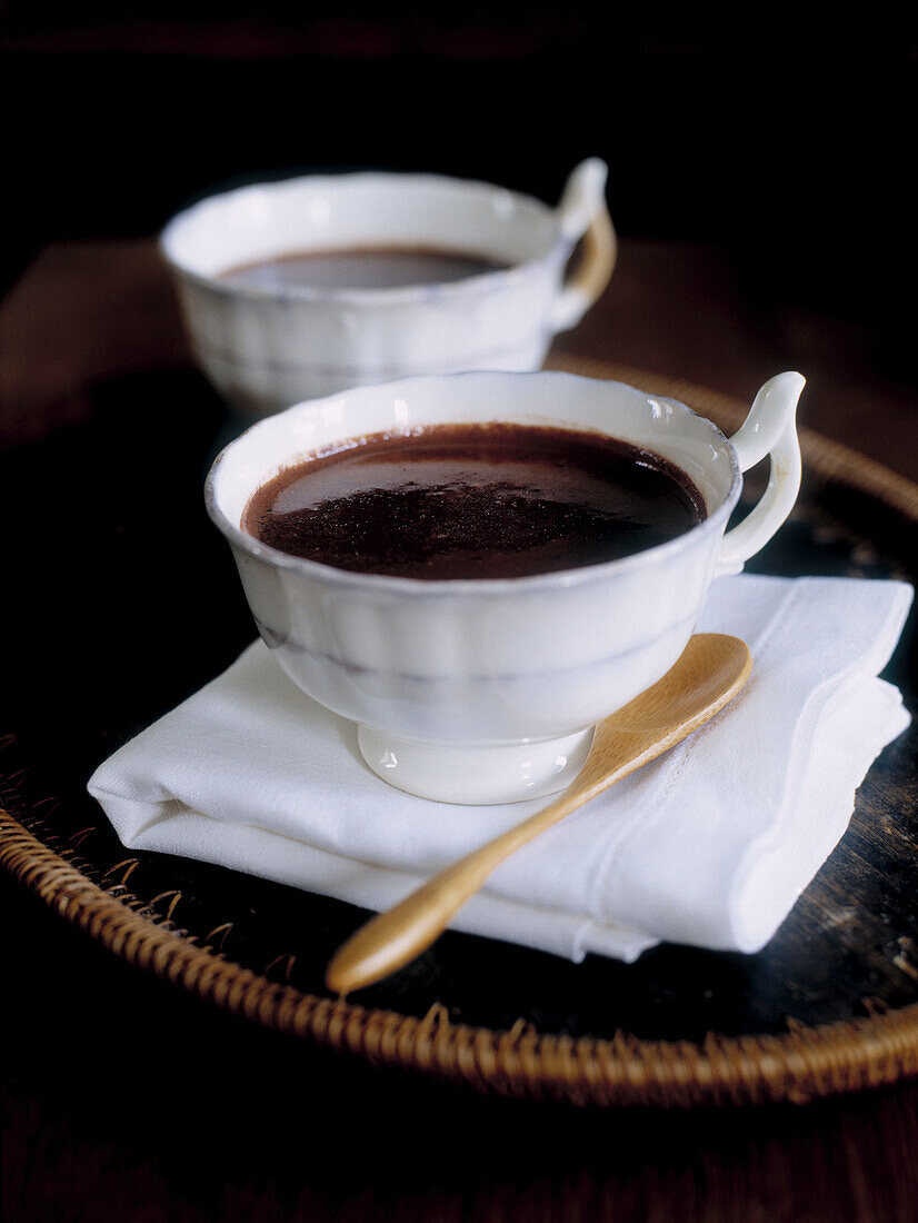 Cup of hot chocolate and wooden spoon with folded napkin on tray