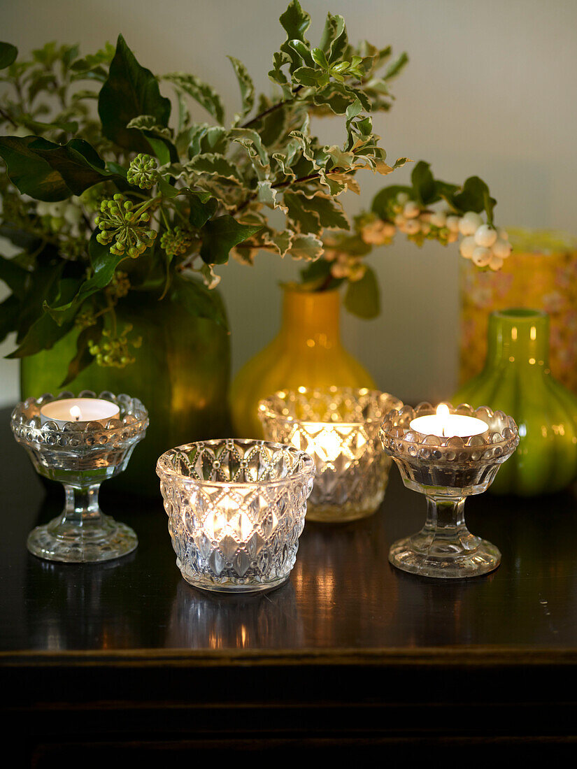 Cut glass tealights with holly in ceramic vases