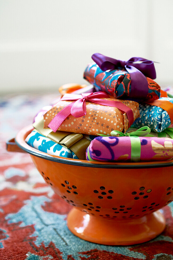 Eingepackte Geschenke in einem leuchtend orangefarbenen Sieb