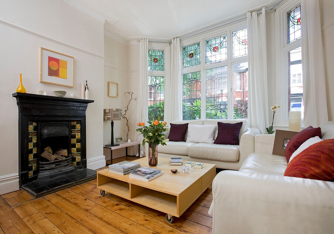 Viktorianischer Kamin und niedriger Couchtisch mit weißen Ledersofas in einem Einfamilienhaus in Manchester, England, Vereinigtes Königreich