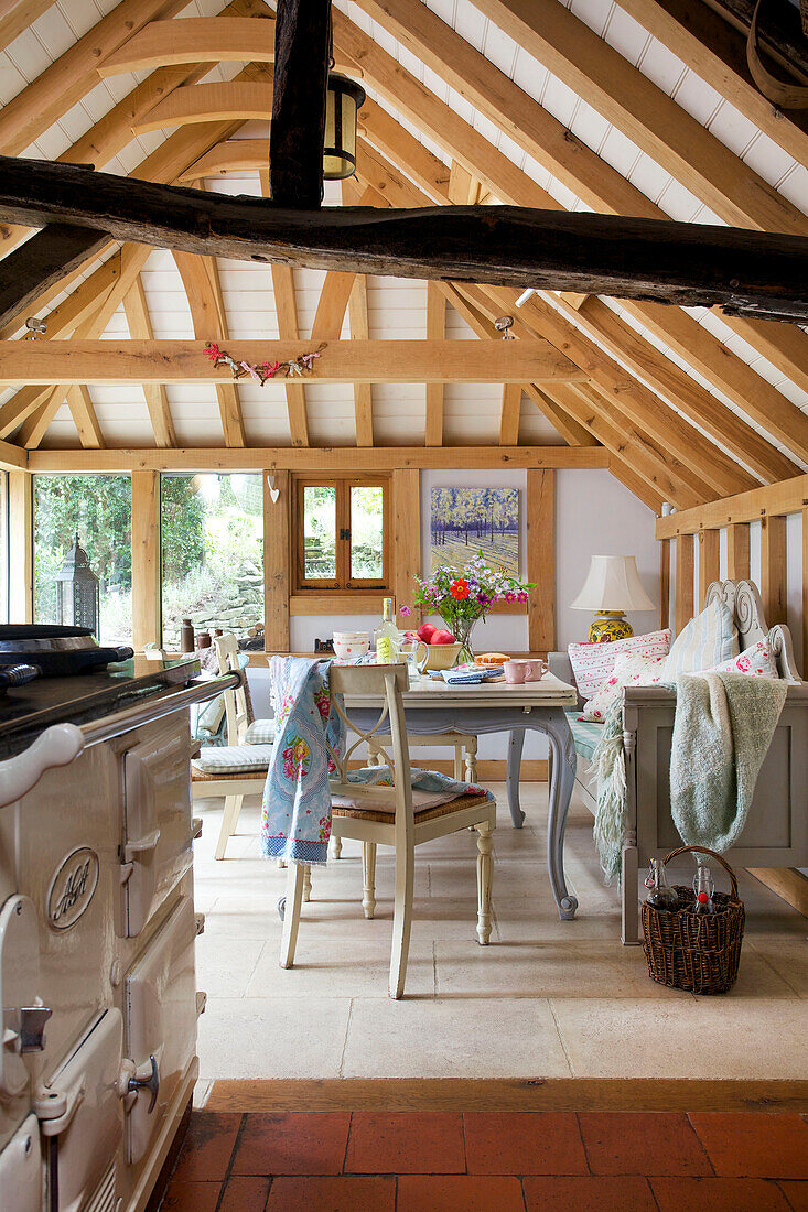 Range oven in beamed kitchen with painted table and seating in Sandhurst cottage, Kent, England, UK