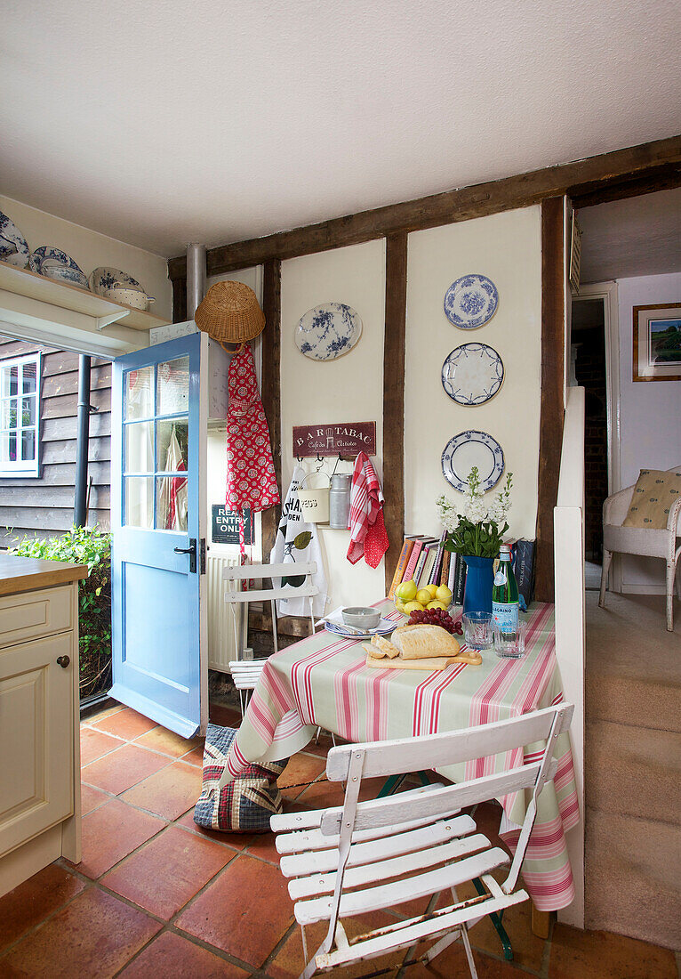 Wall mounted plates in timber framed kitchen with open back door in Egerton, Kent, England, UK