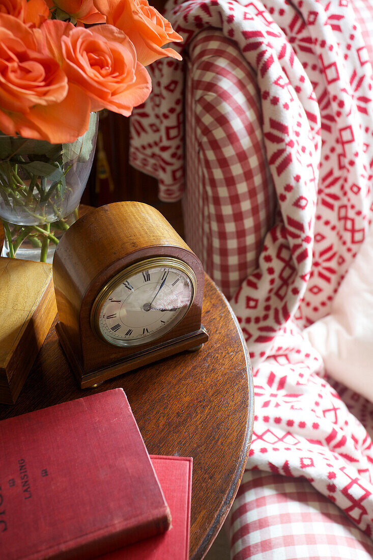 Bücher und Kutschenuhr mit geschnittenen Rosen auf Beistelltisch Egerton cottage, Kent, England, UK