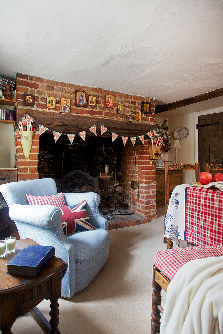 Hellblauer Sessel am Kamin mit Fähnchen in Egerton cottage, Kent, England, UK