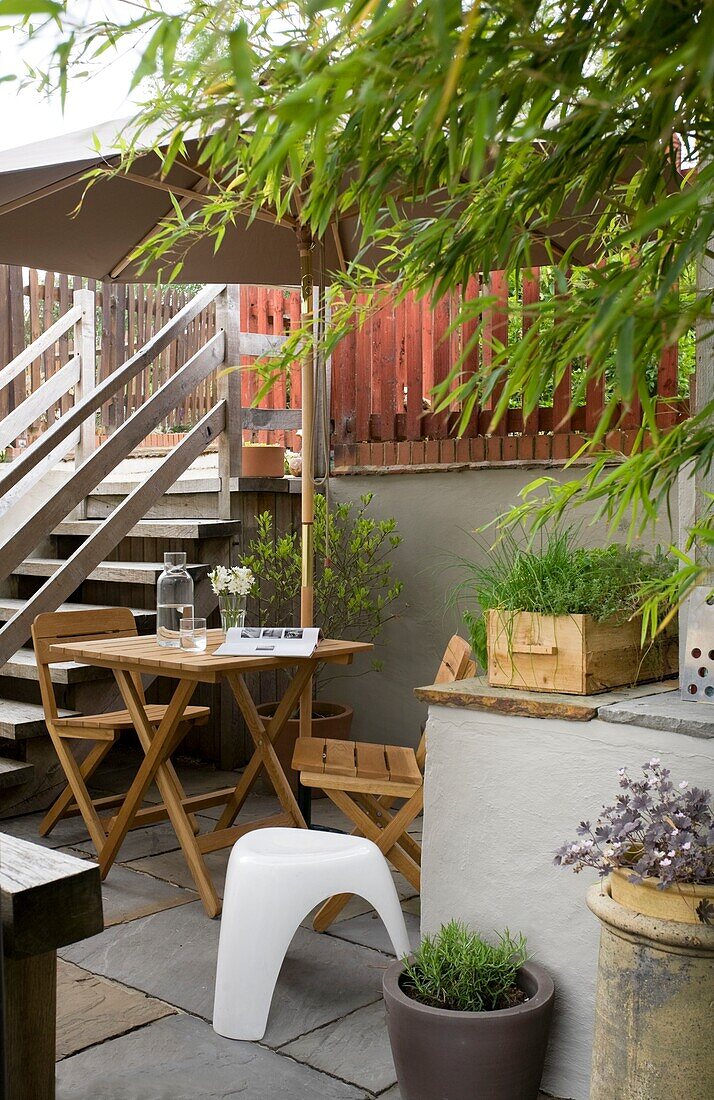 Wooden table and chairs under parasol in back yard with wooden steps