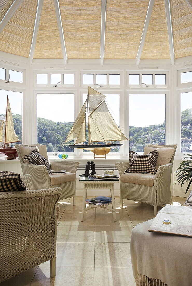 Wicker chairs with model boats in conservatory of Dartmouth home, Devon, UK