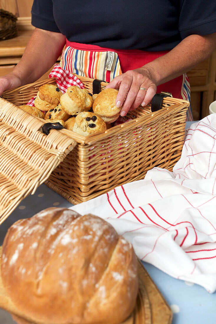 Woman placing scones in picnic basket Dartmouth Devon England UK