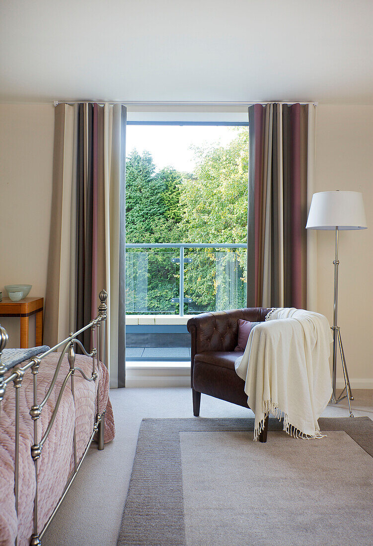 Brown leather armchair at window in bedroom of modern home Bath Somerset, England, UK