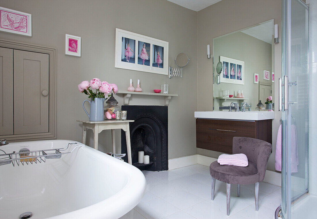 Freestanding rolltop bath with original fireplace and washstand with mirror in Sutton bathroom Alresford Hampshire England UK