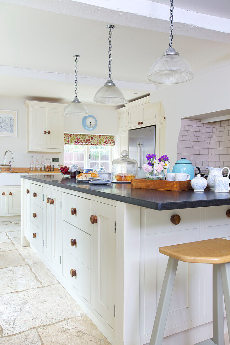 Pink barstool at kitchen island in white fitted kitchen of Bishops Sutton home Alresford Hampshire England UK