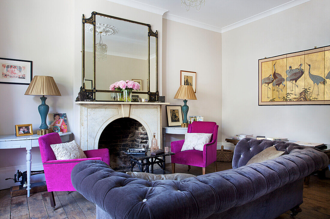 Grey upholstered sofa with pink armchairs in living room of Hackney home London England UK