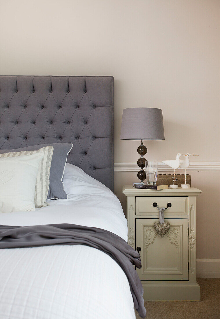 Bird ornaments on painted cabinet with buttoned headboard in Staplehurst bedroom Kent England UK