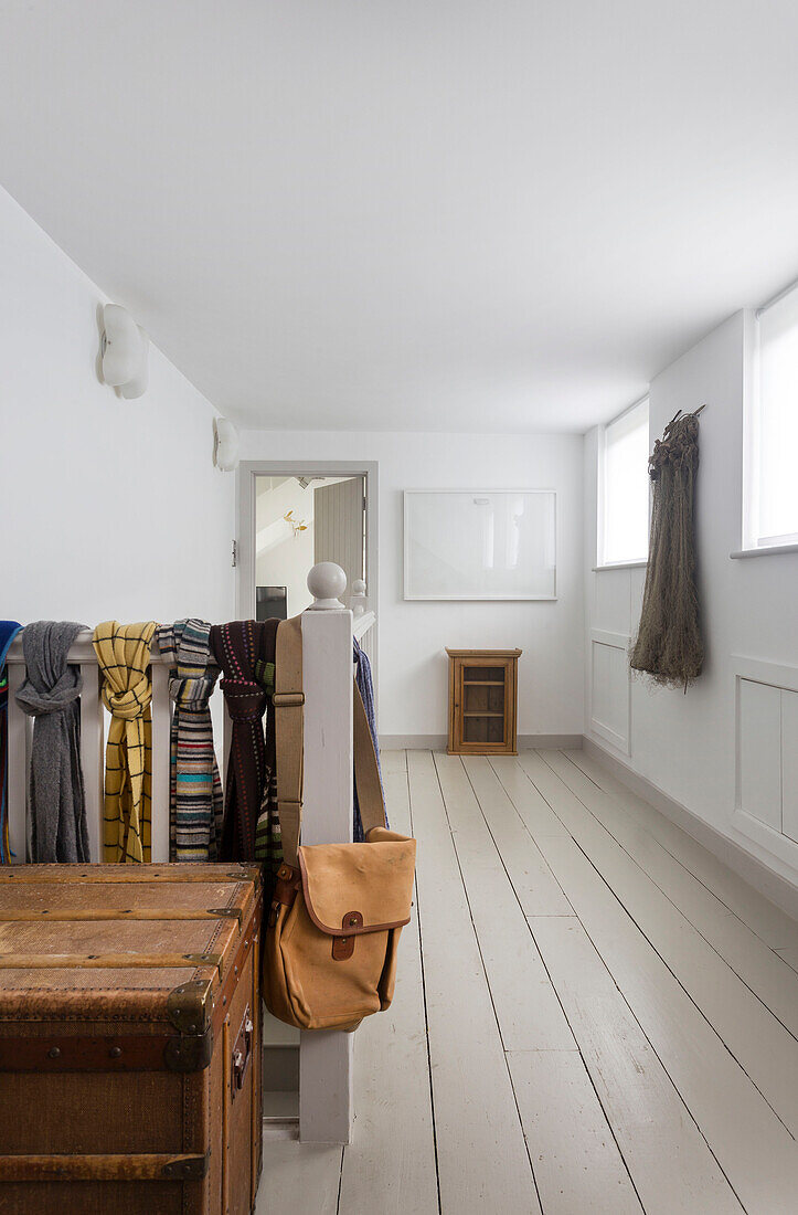 Satchel and scarves on landing banister with vintage trunk in Rye home East Sussex UK