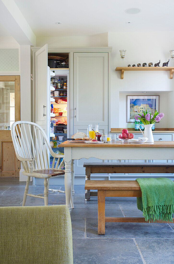 Gestrichener weißer Stuhl am Tisch in der offenen Küche des Hauses in Woodchurch, Kent, England, UK