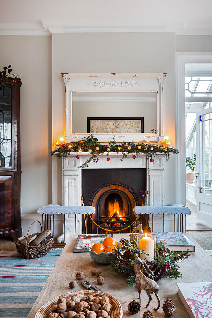 Lit fire and glass fronted cabinet with Christmas decorations in Warehorne rectory Kent UK