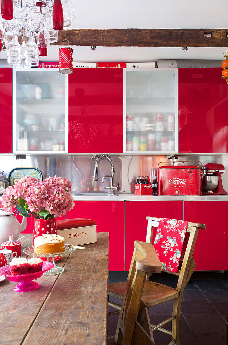 Bright red fitted units and wooden table in Tenterden kitchen Kent UK