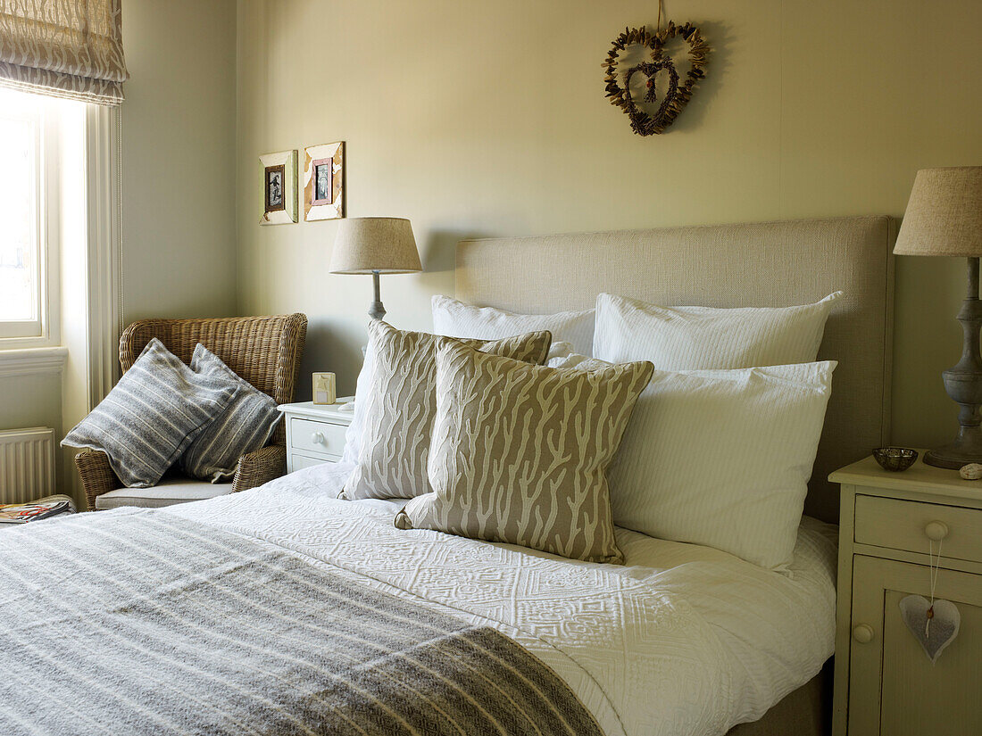 Striped blanket on double bed in room with roman blinds at window in Kensington home London England UK