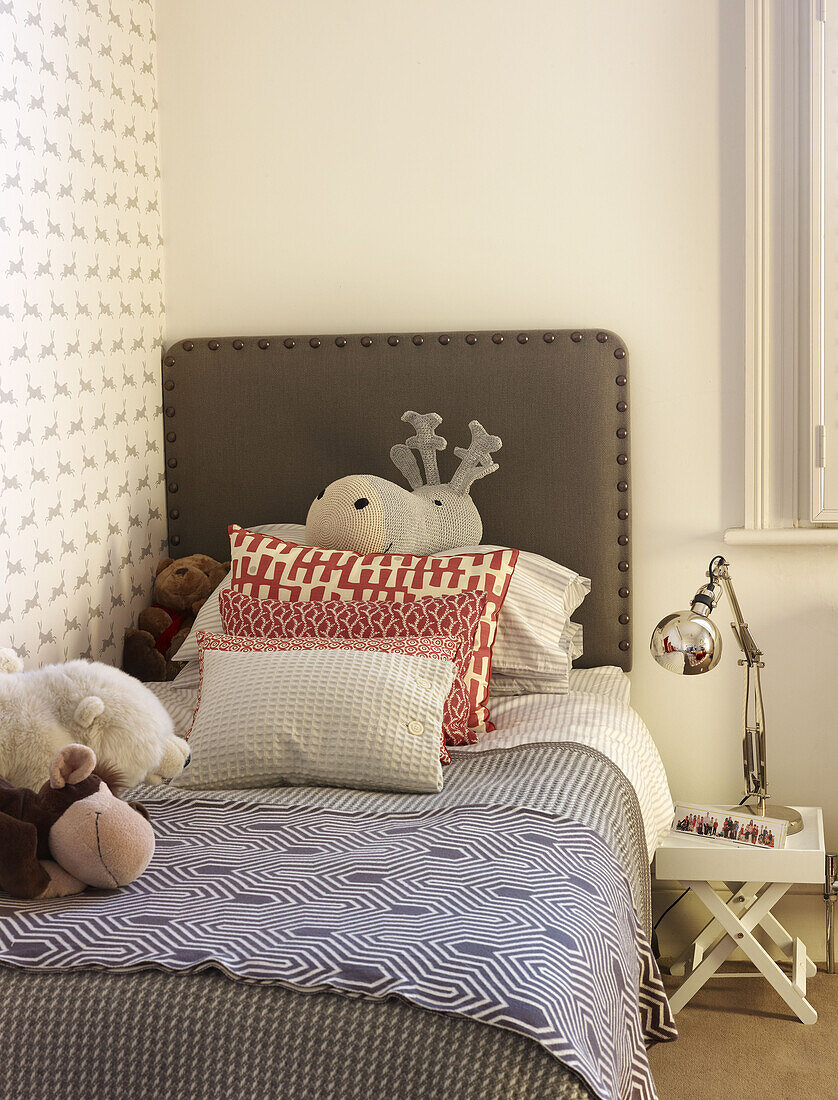 Kuscheltiere und Kissen auf Einzelbett in Kinderzimmer von Londoner Familienhaus England UK